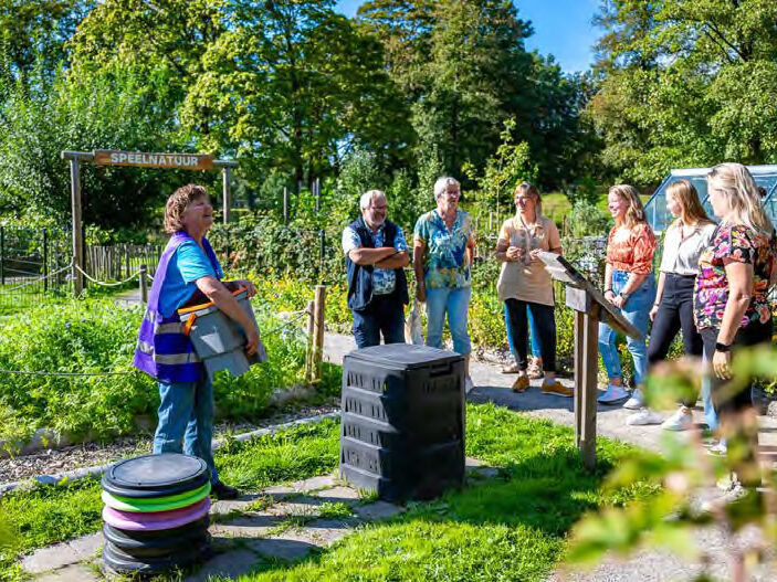 Vrijwilliger geeft tuintoer door de tuin van het Duurzaamheidscentrum Assen voor tips voor een groene tuin