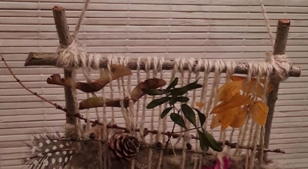 weefraampje met bladeren, bloemen, en wol