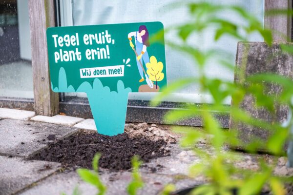 Gewipte tegel met bordje 'Tegel eruit, plant erin. Wij doen mee'.
