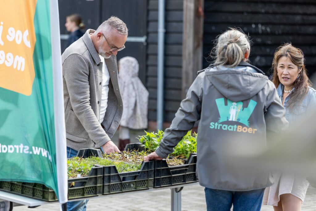 Een man kijkt naar de plantjes van de kraam van Stichting Straatboer