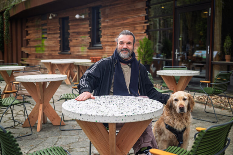 Melle met een hond zit aan een van de nieuwe terrastafels