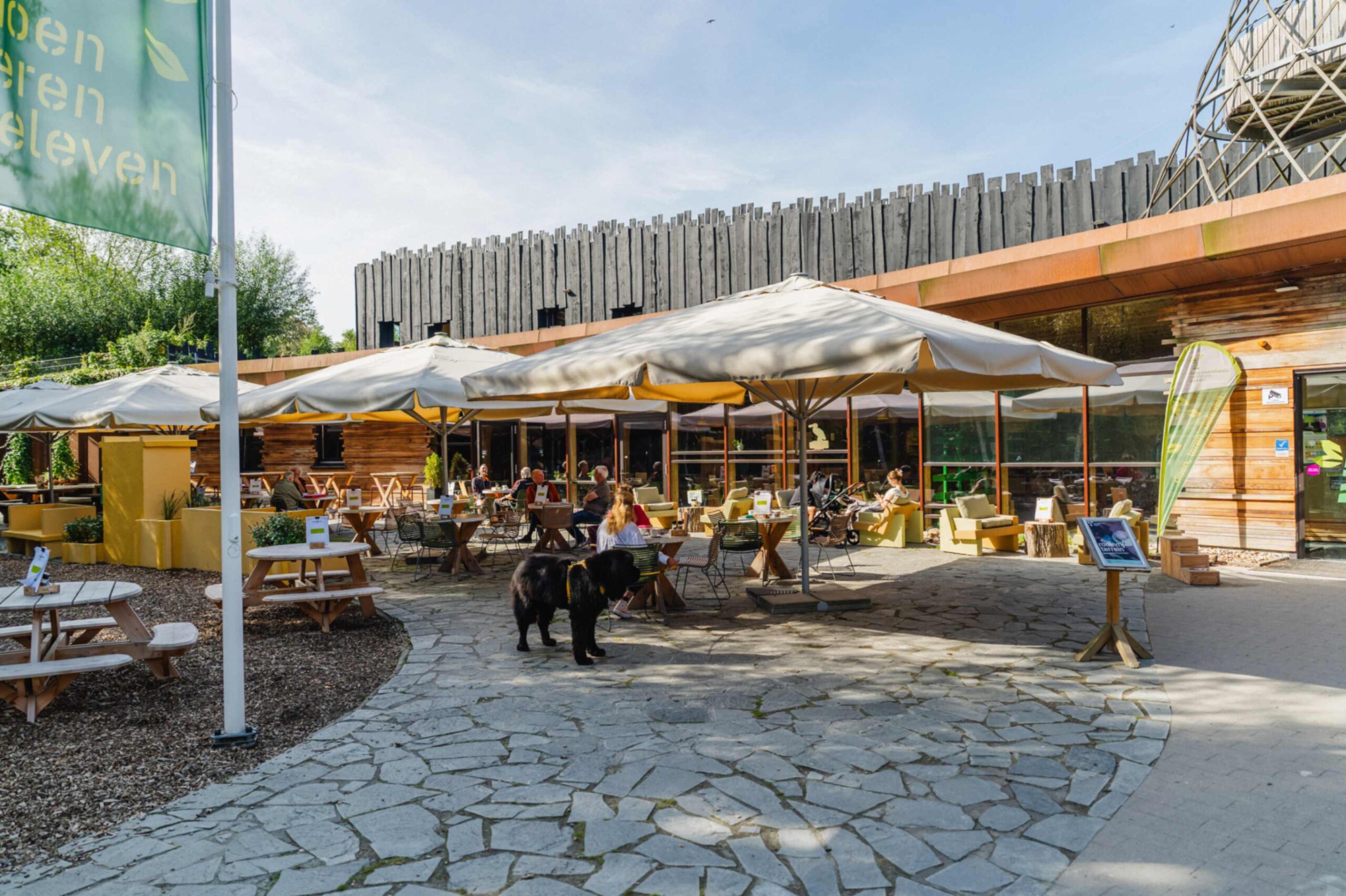 Het terras van het Eetlokaal van het Duurzaamheidscentrum Assen, met terrastafels, picknickbanken en parasols